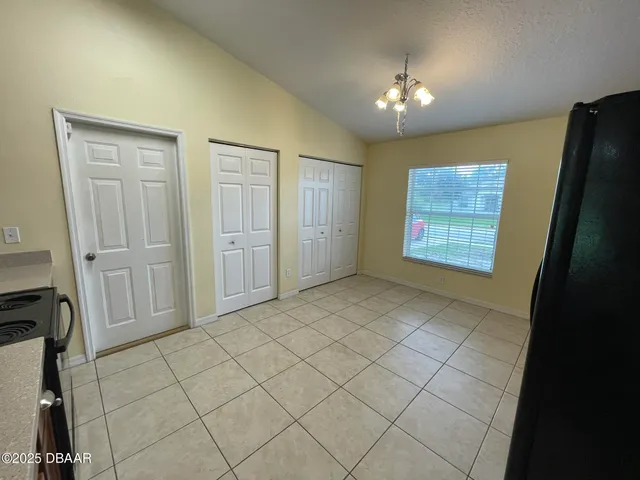 an empty room with chandelier fan and windows