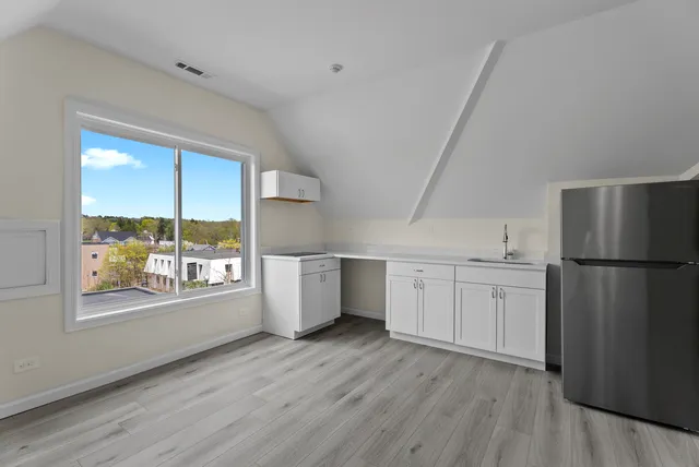 a kitchen with a refrigerator a sink and dishwasher with wooden floor