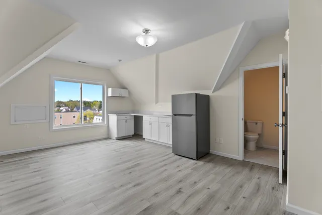 a view of hallway with wooden floor and a refrigerator