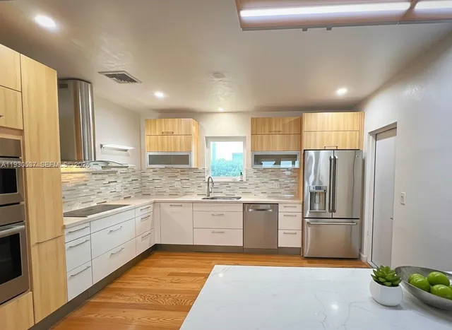 a kitchen with stainless steel appliances granite countertop a refrigerator and a sink