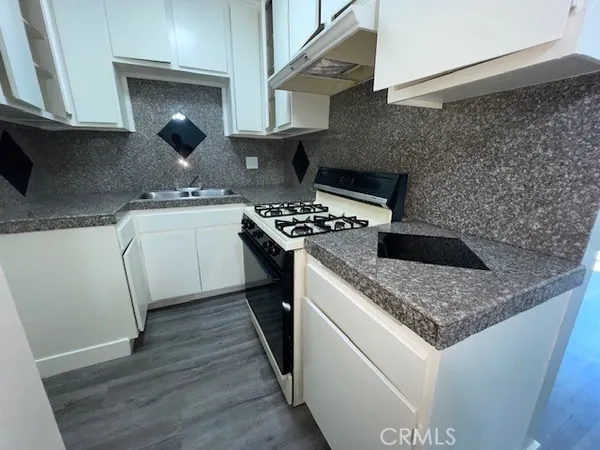 a kitchen with granite countertop a sink stove and refrigerator