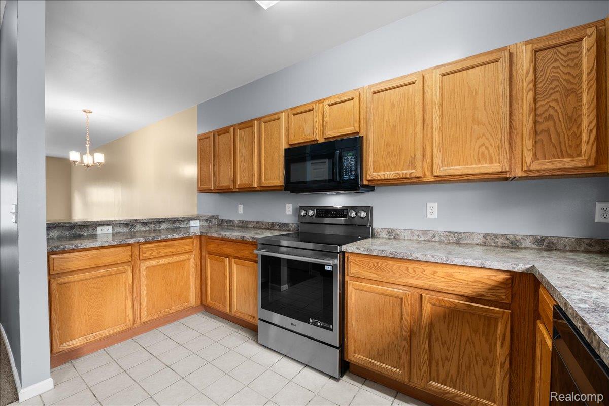 22684 Goddard Road Taylor, MI 48180 - Photo 7 of 29 Kitchen featuring warm-toned wood cabinetry, stone-look countertops, stainless steel electric range, and an over-the-range microwave