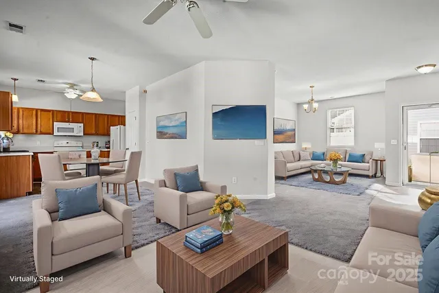 a living room with furniture kitchen view and a chandelier