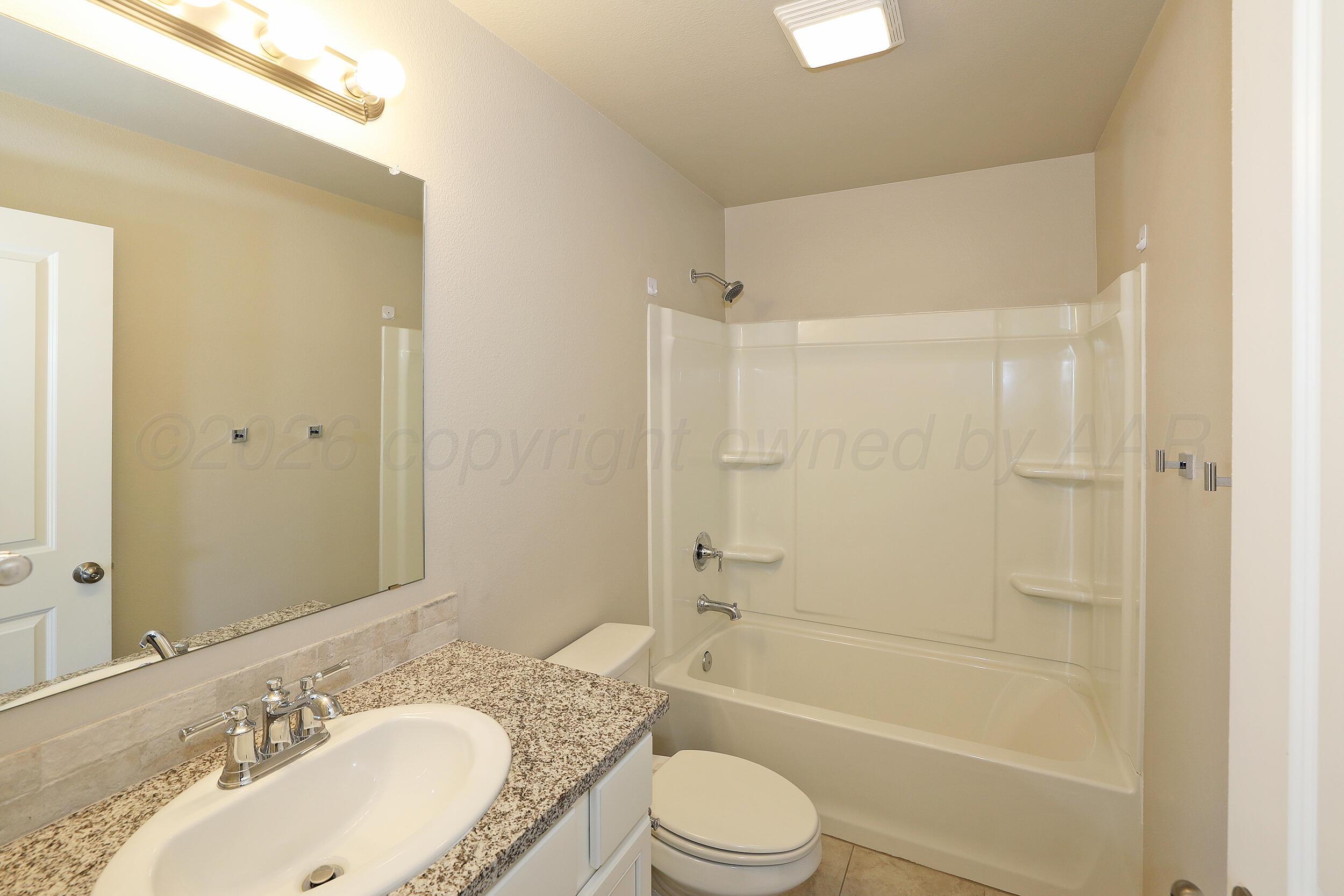 7205 Athens Street Amarillo, TX 79118 - Photo 17 of 25 a bathroom with a granite countertop bathtub shower sink mirror vanity and a toilet