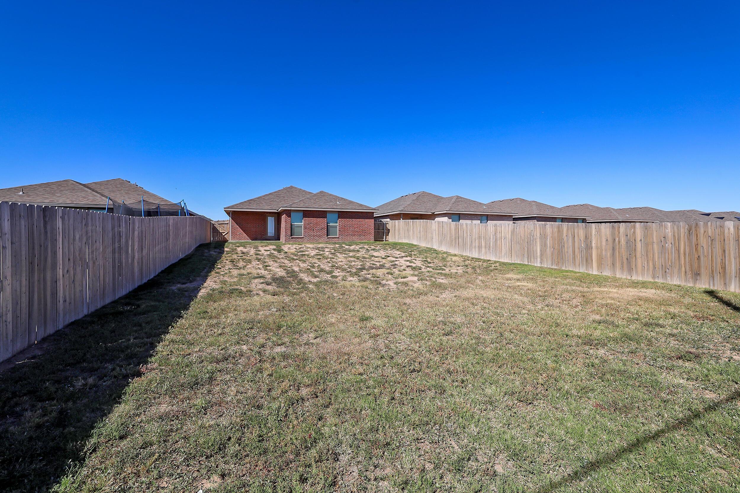 7205 Athens Street Amarillo, TX 79118 - Photo 19 of 25 a view of a backyard with a garden and wooden fence