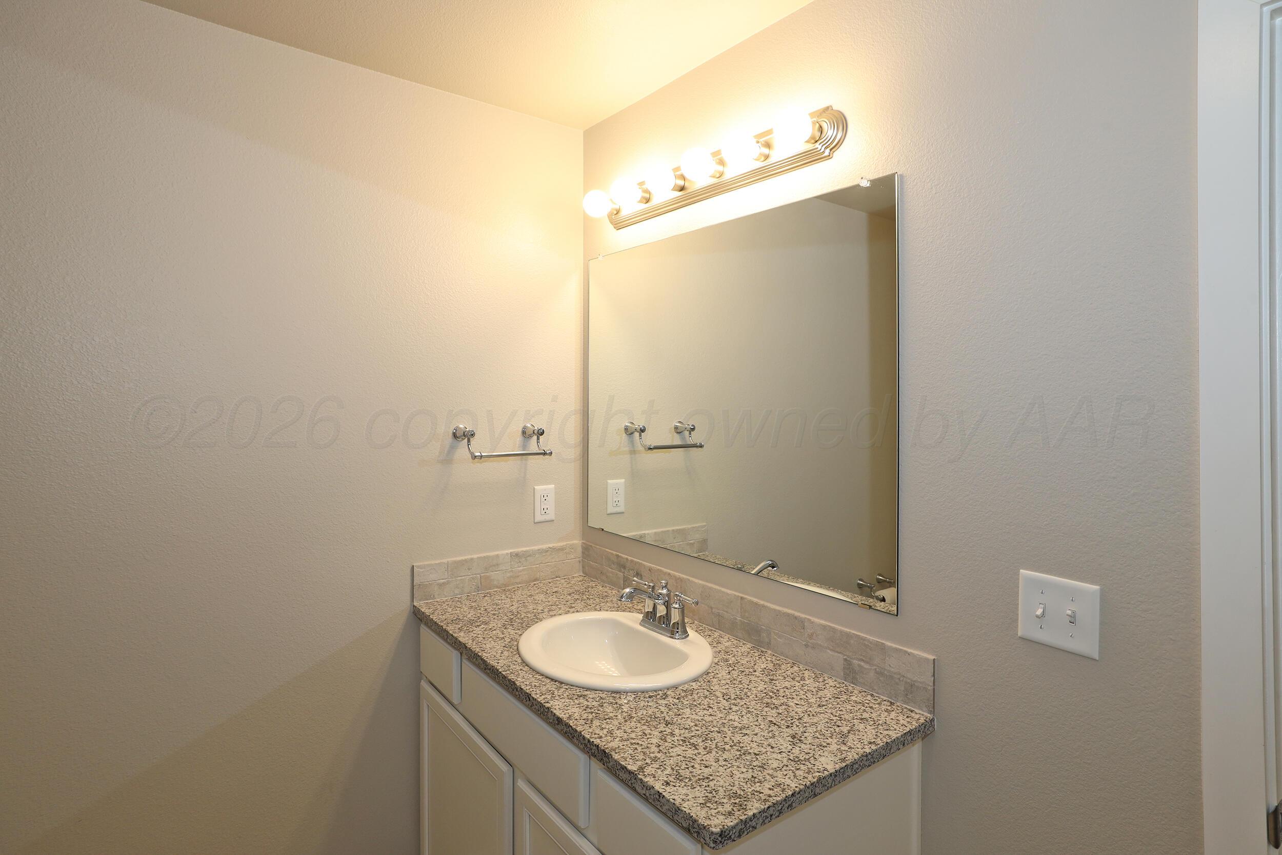 7205 Athens Street Amarillo, TX 79118 - Photo 20 of 25 a bathroom with a granite countertop sink and a mirror