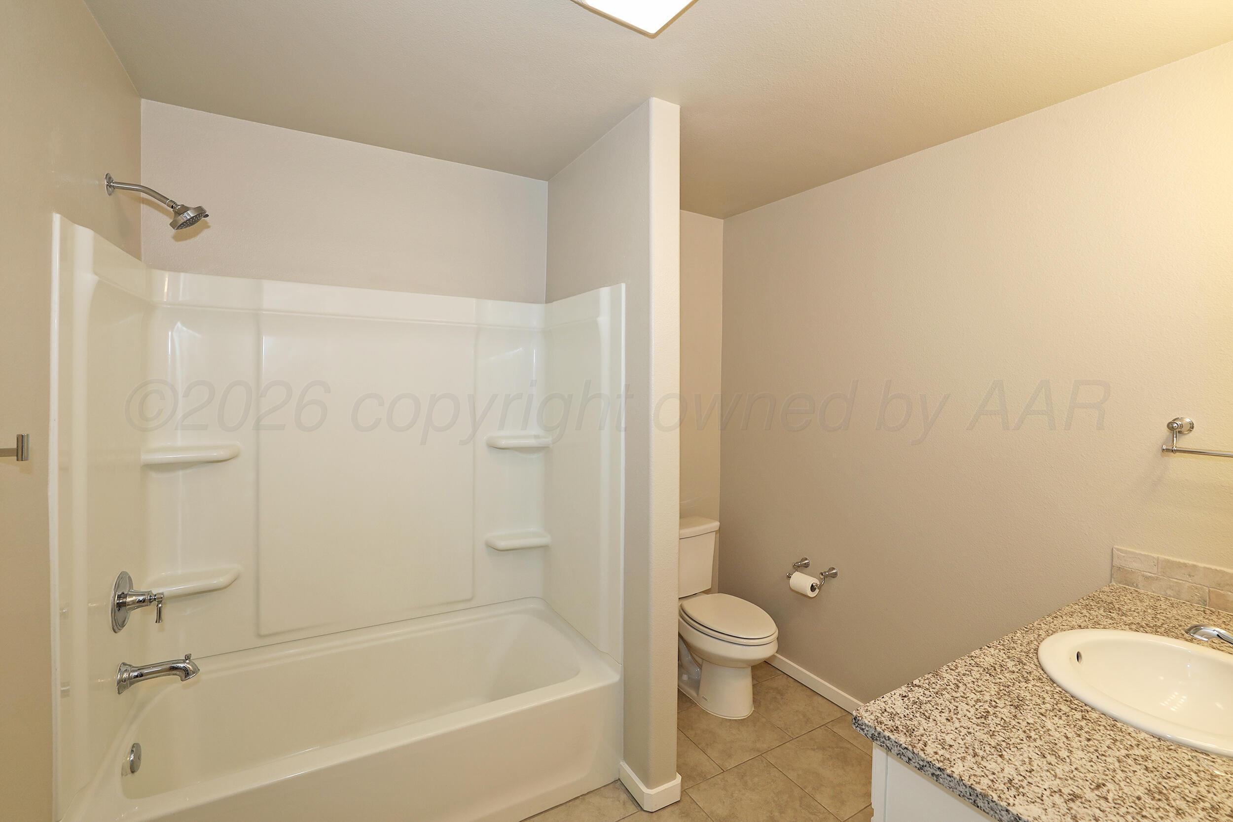 7205 Athens Street Amarillo, TX 79118 - Photo 21 of 25 a bath room with a granite countertop toilet and a sink