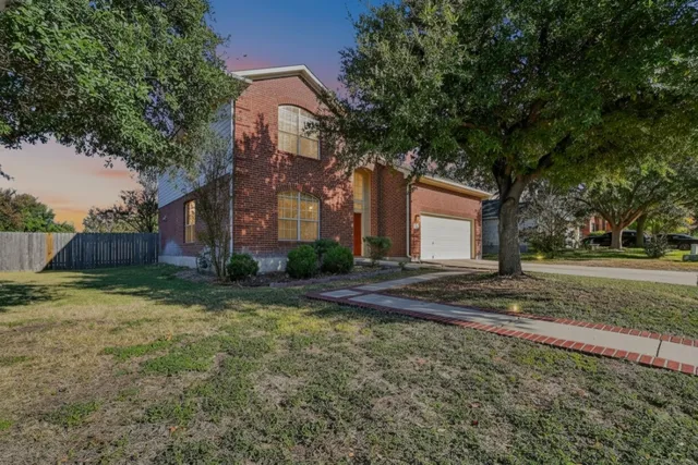 a view of a house with a yard and large tree