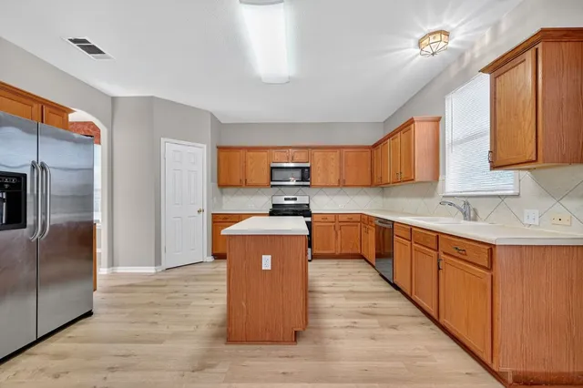 a large kitchen with stainless steel appliances granite countertop a stove a sink dishwasher and a refrigerator