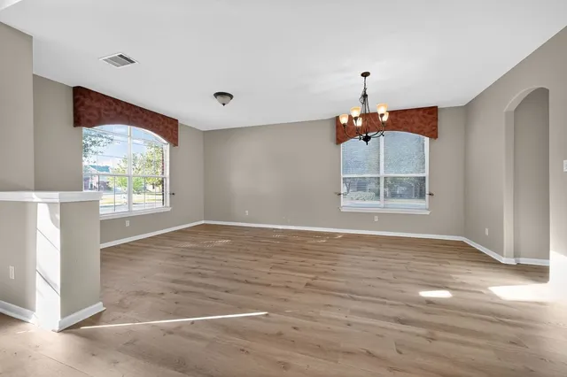 a view of an empty room with window and wooden floor