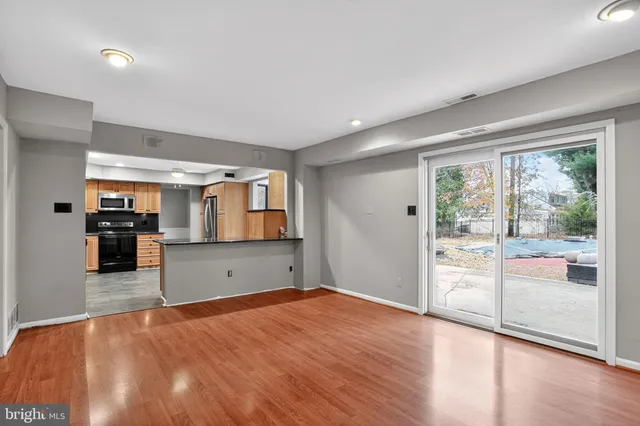 a living room with stainless steel appliances kitchen island granite countertop a refrigerator cabinets and wooden floor