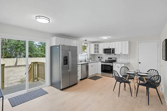 a kitchen with a refrigerator a stove a sink and a dining table with wooden floor