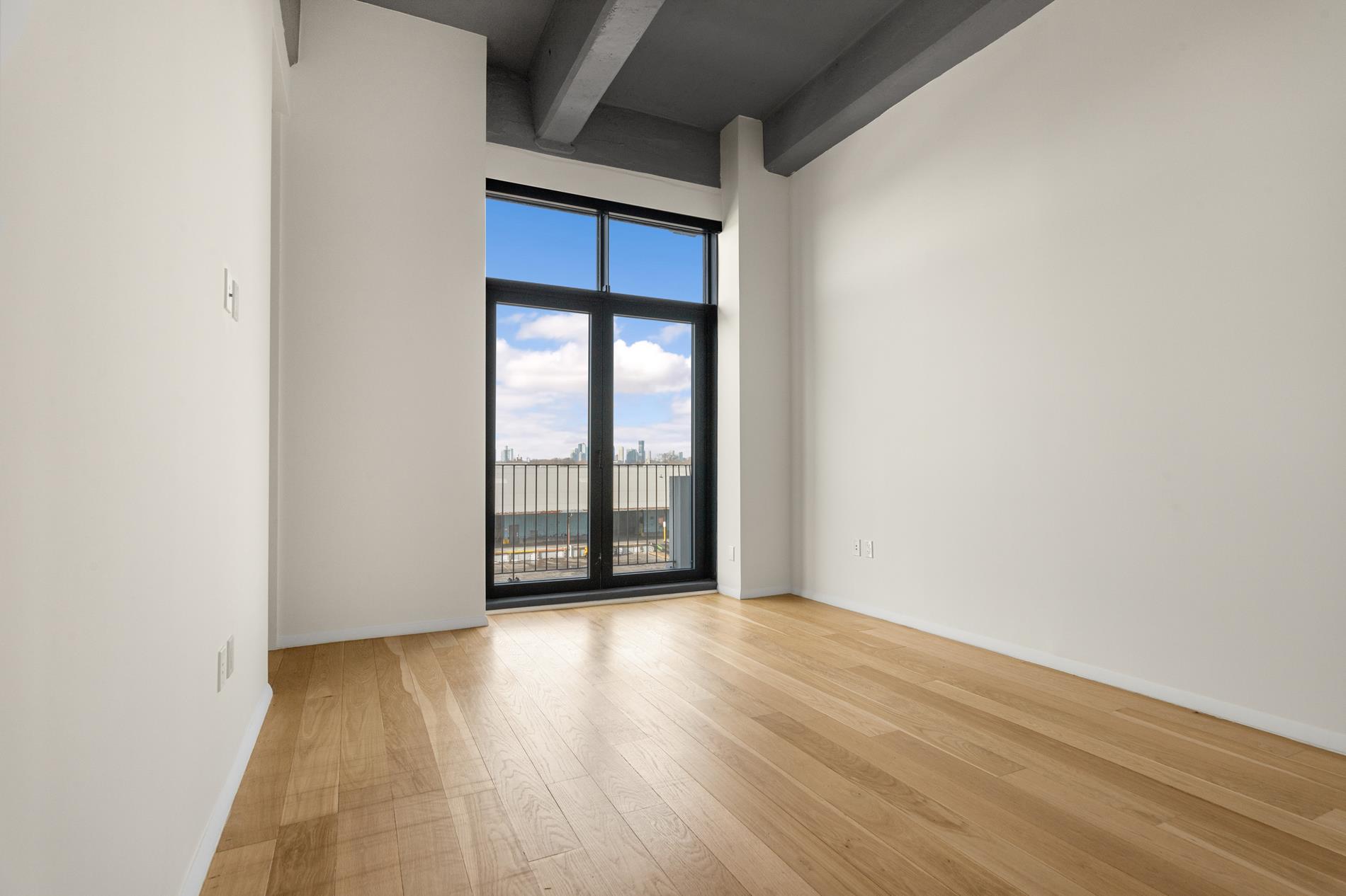 160 Imlay Street, Unit 3B2 Brooklyn, NY 11231 - Photo 8 of 18 a view of an empty room with wooden floor and a window