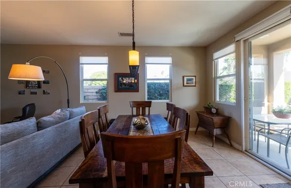 a kitchen with stainless steel appliances granite countertop a refrigerator a sink dishwasher a dining table and chairs with wooden floor