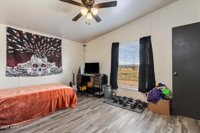 a bedroom with a bed a computer on a desk and a book shelf