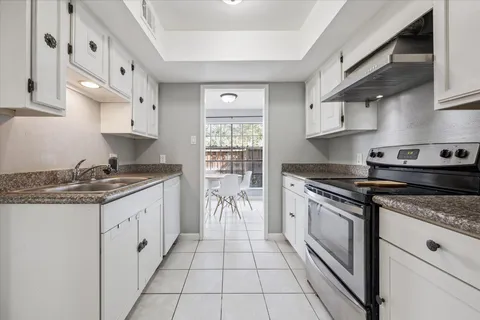 a kitchen with granite countertop a stove sink and cabinets