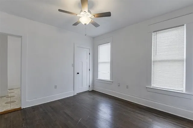 an empty room with wooden floor ceiling fan and windows