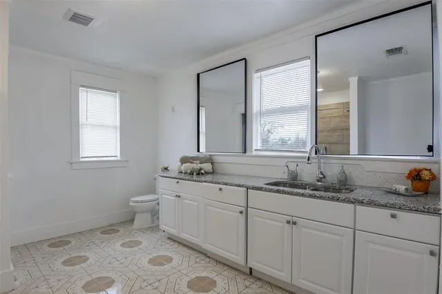 a bathroom with 2 sink toilet and a mirror