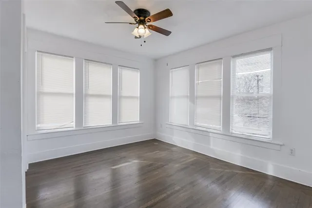 an empty room with wooden floor fan and windows