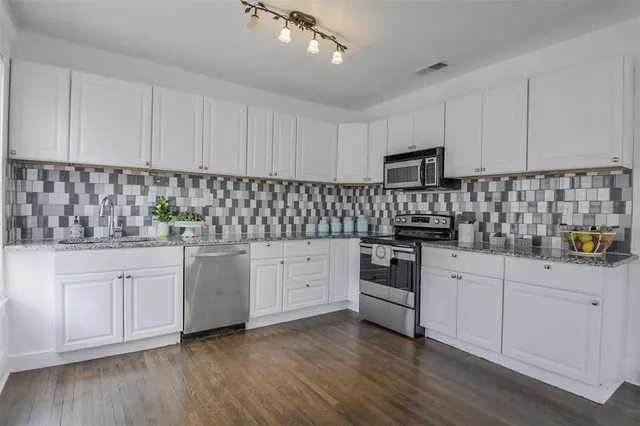 a kitchen with granite countertop white cabinets and white appliances