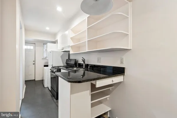 a kitchen with a sink and a stove top oven with wooden floor