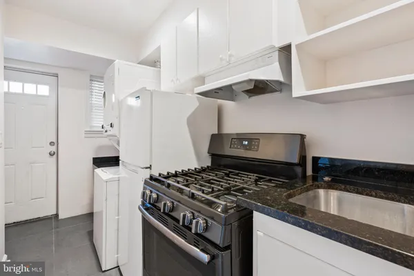 a kitchen with stainless steel appliances granite countertop white cabinets and a stove