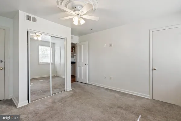an empty room with closet and a ceiling fan