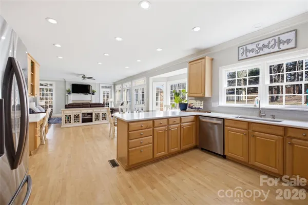 a large kitchen with stainless steel appliances granite countertop a large center island and a view of living room