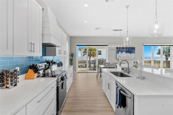 a large white kitchen with lots of counter space a sink appliances and cabinets