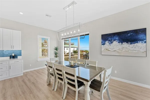 a view of a dining room and livingroom with furniture wooden floor a chandelier