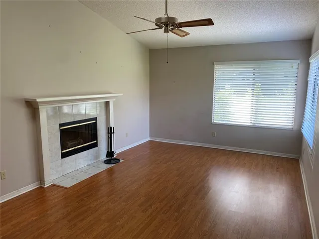 an empty room with wooden floor fireplace and windows