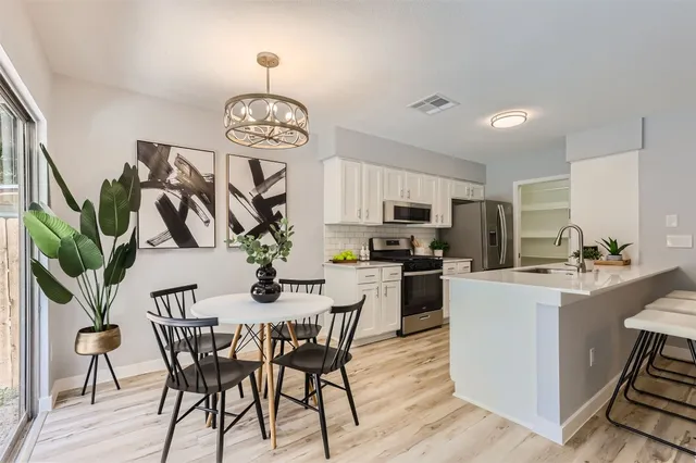 a kitchen with a table chairs stove and white cabinets