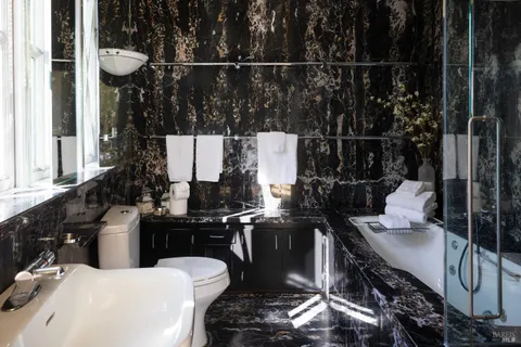 a view of a white house next to a yard with potted plants