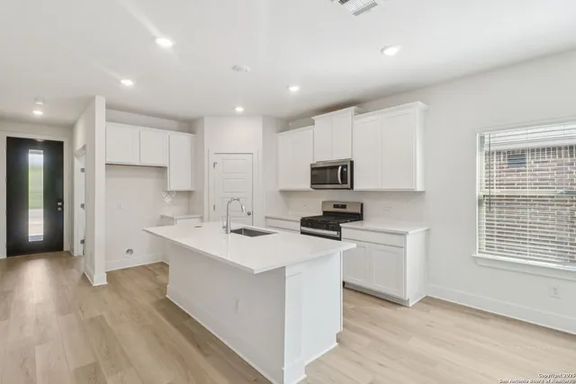 a kitchen with stainless steel appliances a sink a stove a refrigerator cabinets and a window