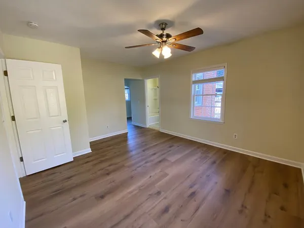 a view of an empty room with wooden floor and a window