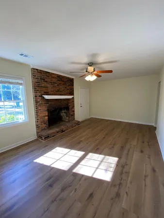 an empty room with wooden floor fireplace and windows
