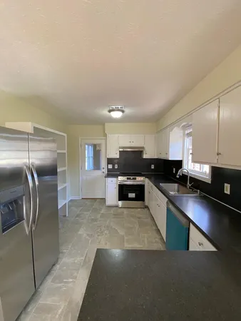 a large kitchen with stainless steel appliances kitchen island a large counter top and a refrigerator