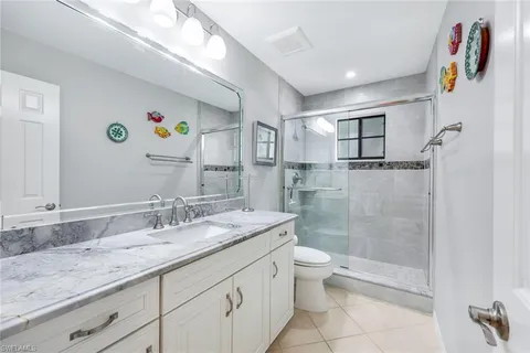 a bathroom with a granite countertop sink a toilet a shower and a mirror