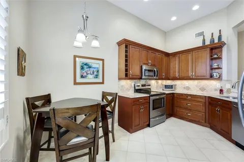 a kitchen with stainless steel appliances granite countertop a stove top oven a sink dishwasher and a refrigerator with wooden cabinets