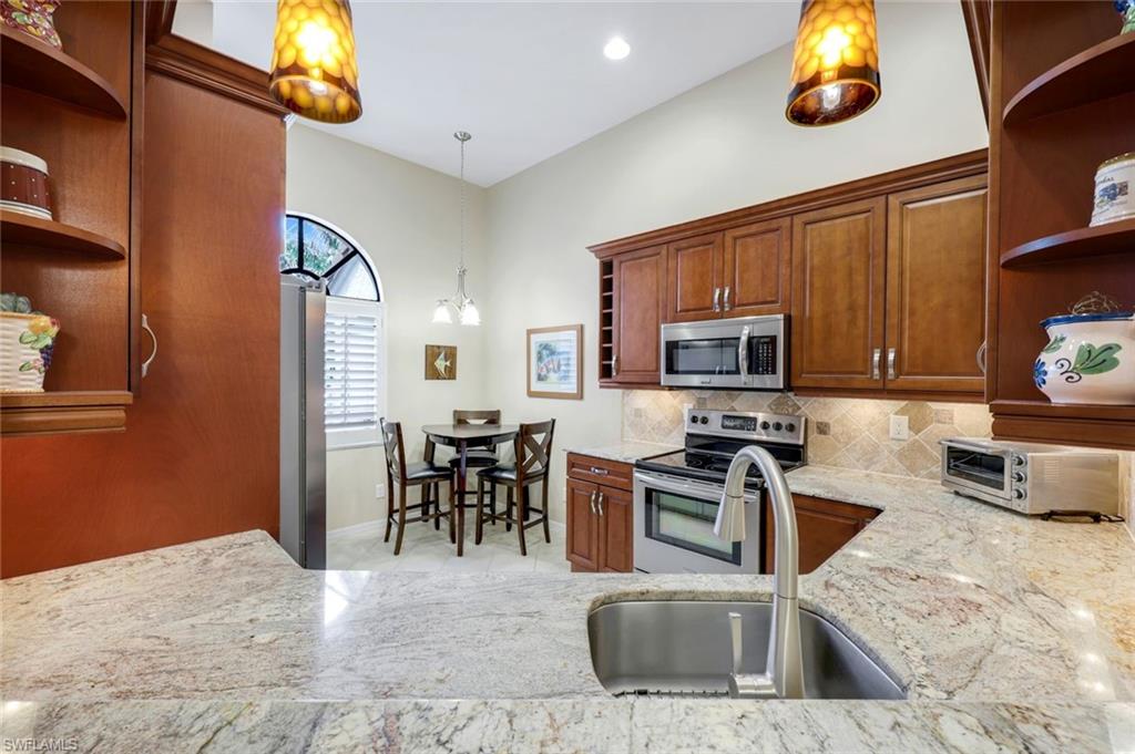 6555 Valen Way, Unit G201 Naples, FL 34108 - Photo 7 of 26 a kitchen with stainless steel appliances granite countertop a sink stove and microwave