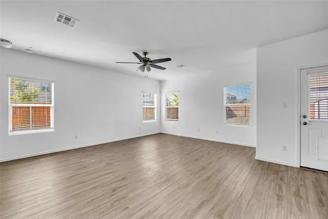 a view of an empty room with a window and wooden floor