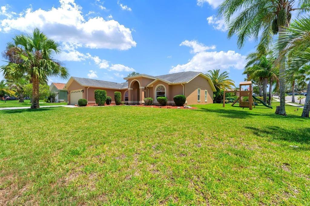 10228 Yellow Pine Way Hudson, FL 34667 - Photo 3 of 22 a view of a house with a big yard and palm trees