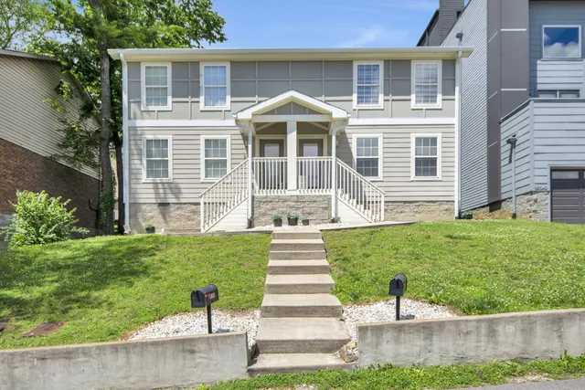 a front view of a house with a yard and potted plants
