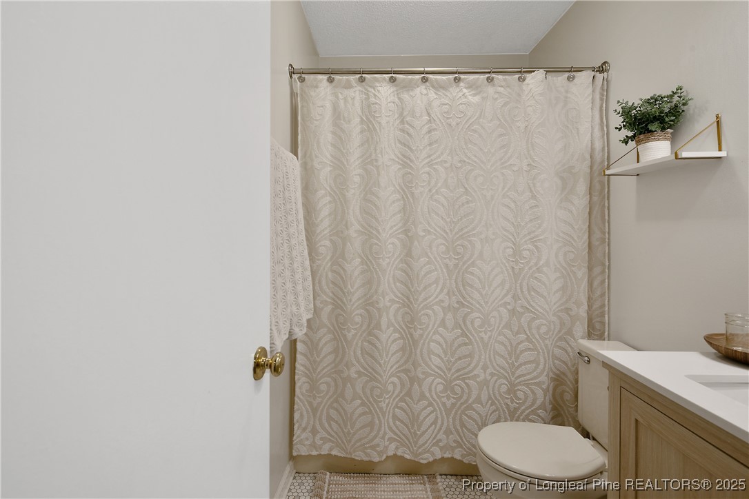 64 California Lane Spring Lake, NC 28390 - Photo 37 of 50 a white toilet sitting next to a shower curtain