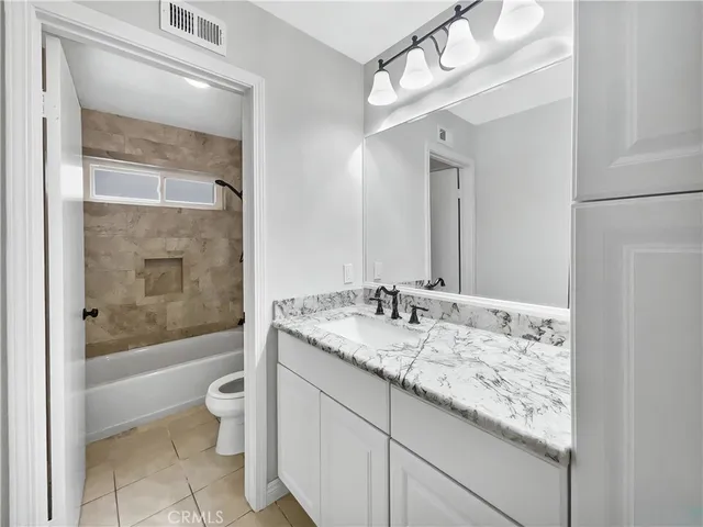 a bathroom with a granite countertop sink a toilet and bathtub
