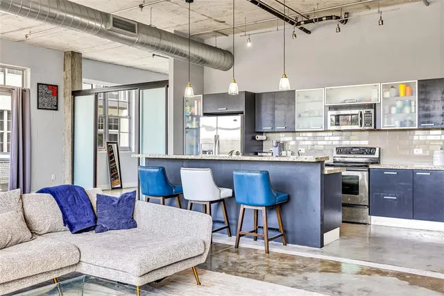 a living room with stainless steel appliances granite countertop furniture a fireplace and a chandelier
