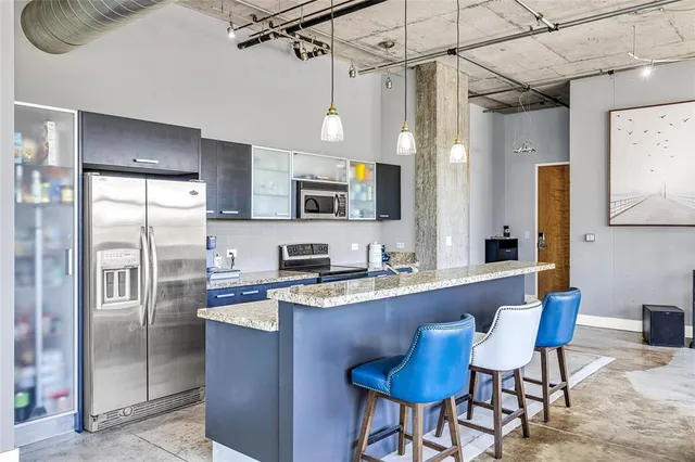 a kitchen with stainless steel appliances granite countertop a sink a stove a refrigerator cabinets and a dining table