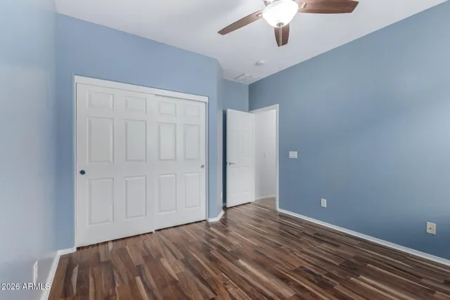 an empty room with a chandelier fan and wooden floor
