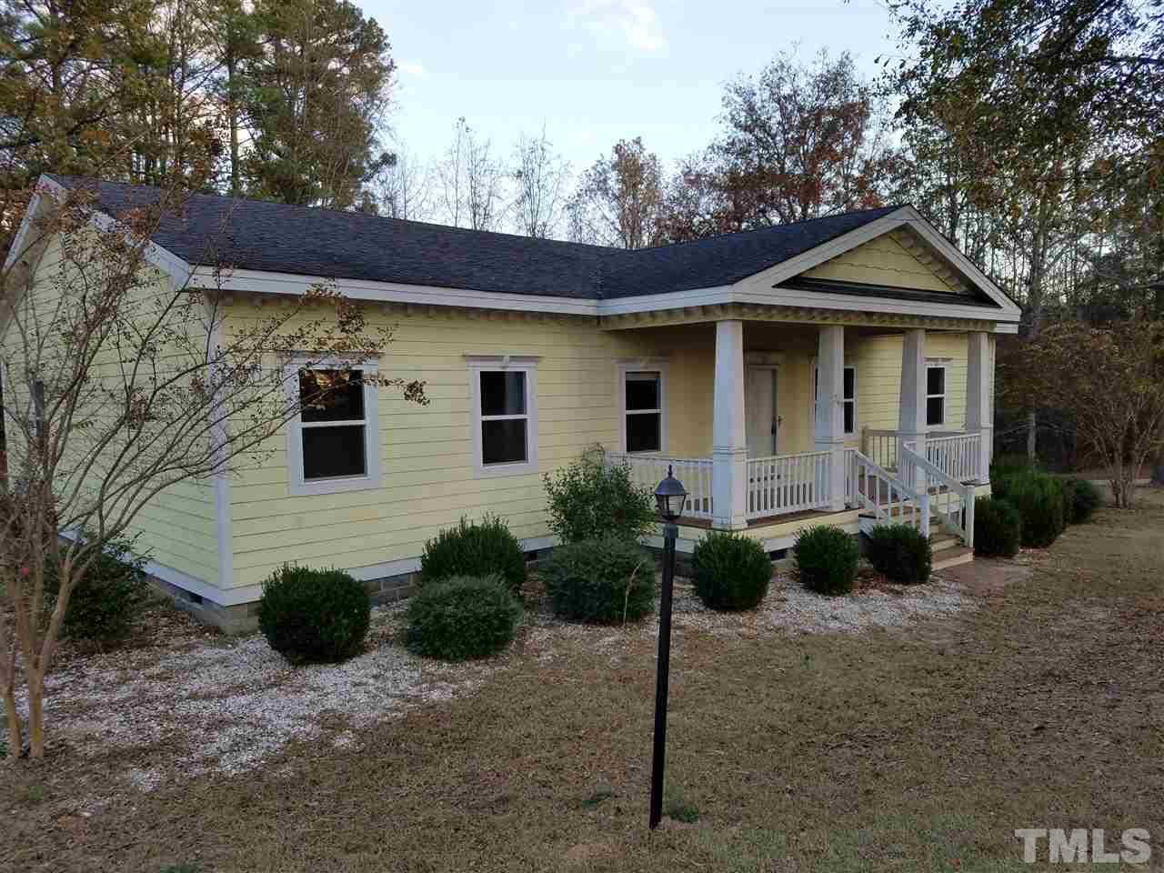 a view of a white house next to a yard with plants and trees