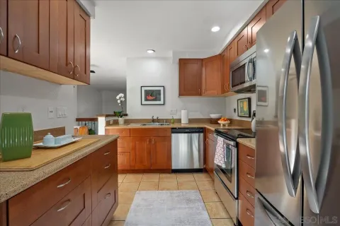 a kitchen with stainless steel appliances granite countertop a refrigerator a stove and a sink